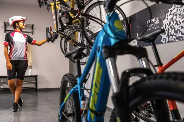 Ciclista che osserva una bicicletta appesa in una stanza con altre bici in esposizione.