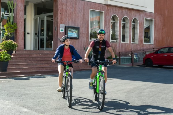Due persone in bicicletta davanti a un edificio.